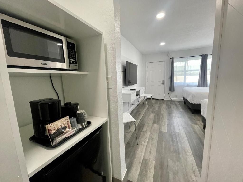 A hotel room with a microwave , refrigerator , coffee maker and television.