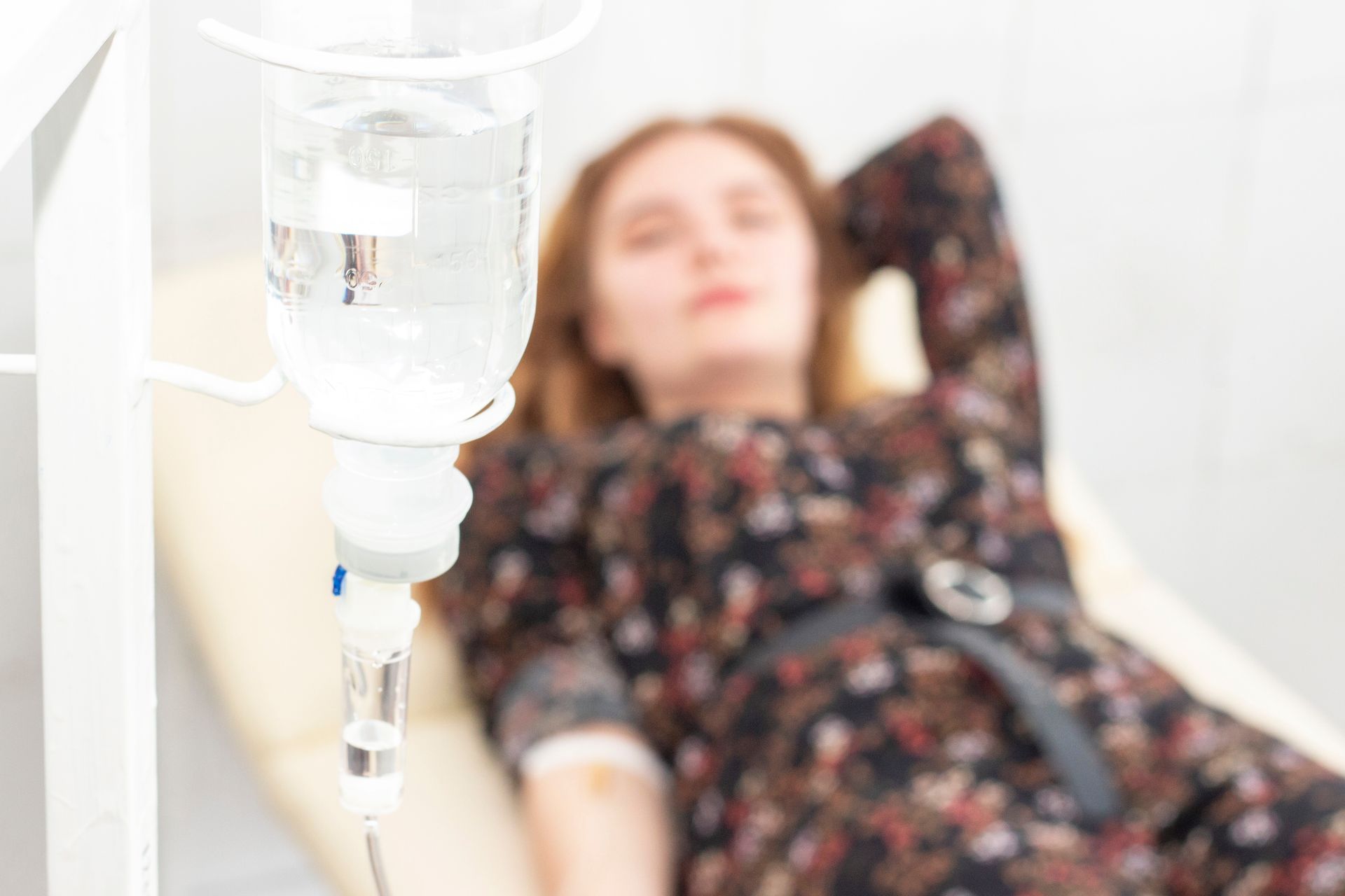 A woman is laying in a hospital bed with an iv in her arm.