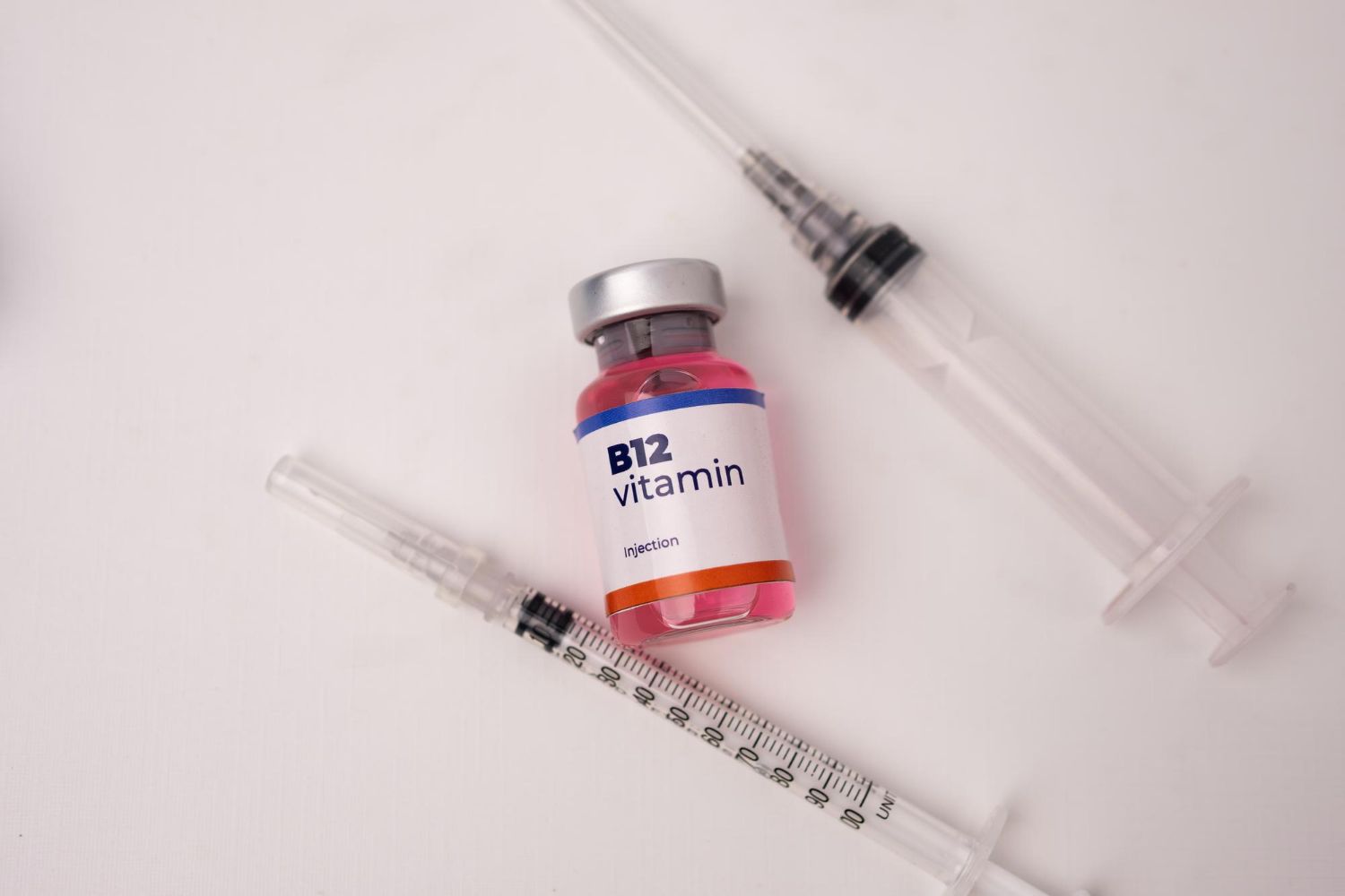 A bottle of b12 vitamin next to a syringe on a table.