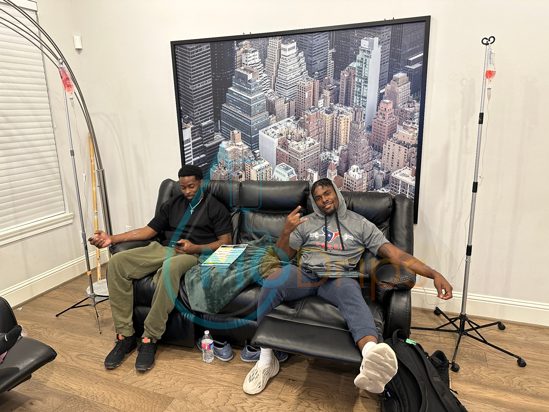 Two men are sitting on a couch in a living room.