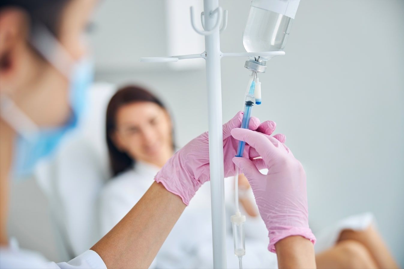 A nurse is preparing an iv for a patient in a hospital bed.