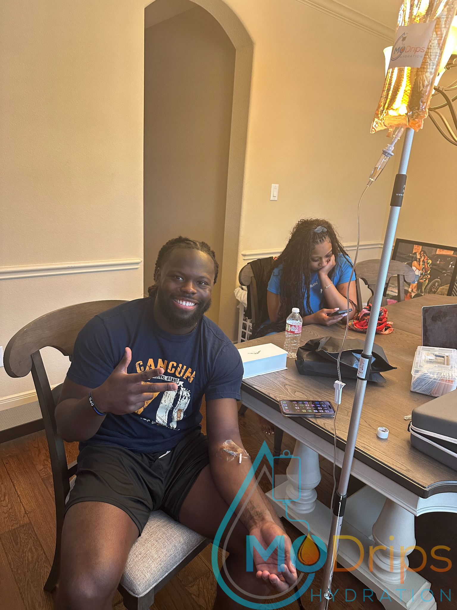 A man is sitting at a table with an iv in his arm.