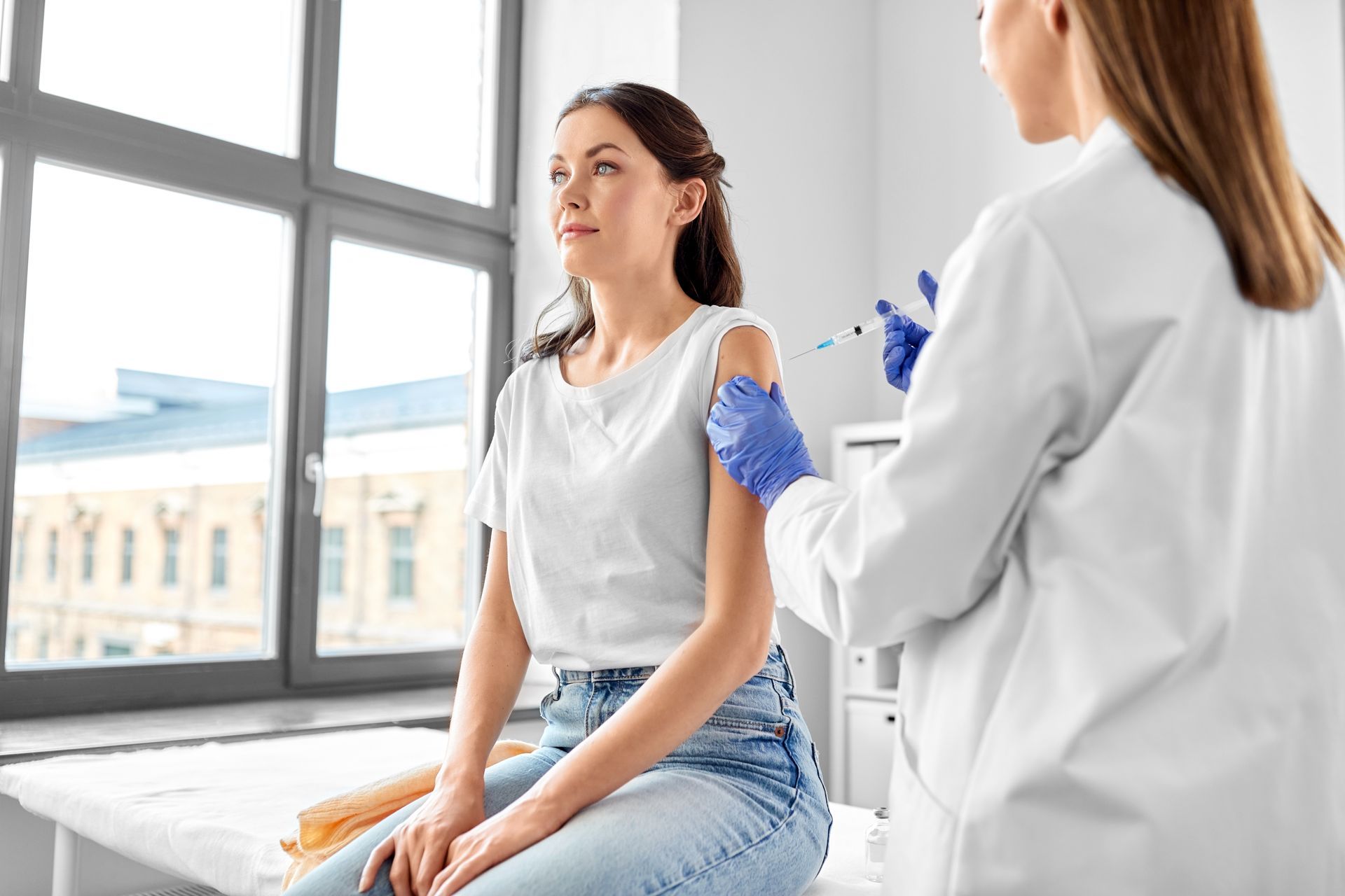 A woman is getting an injection in her arm by a doctor.