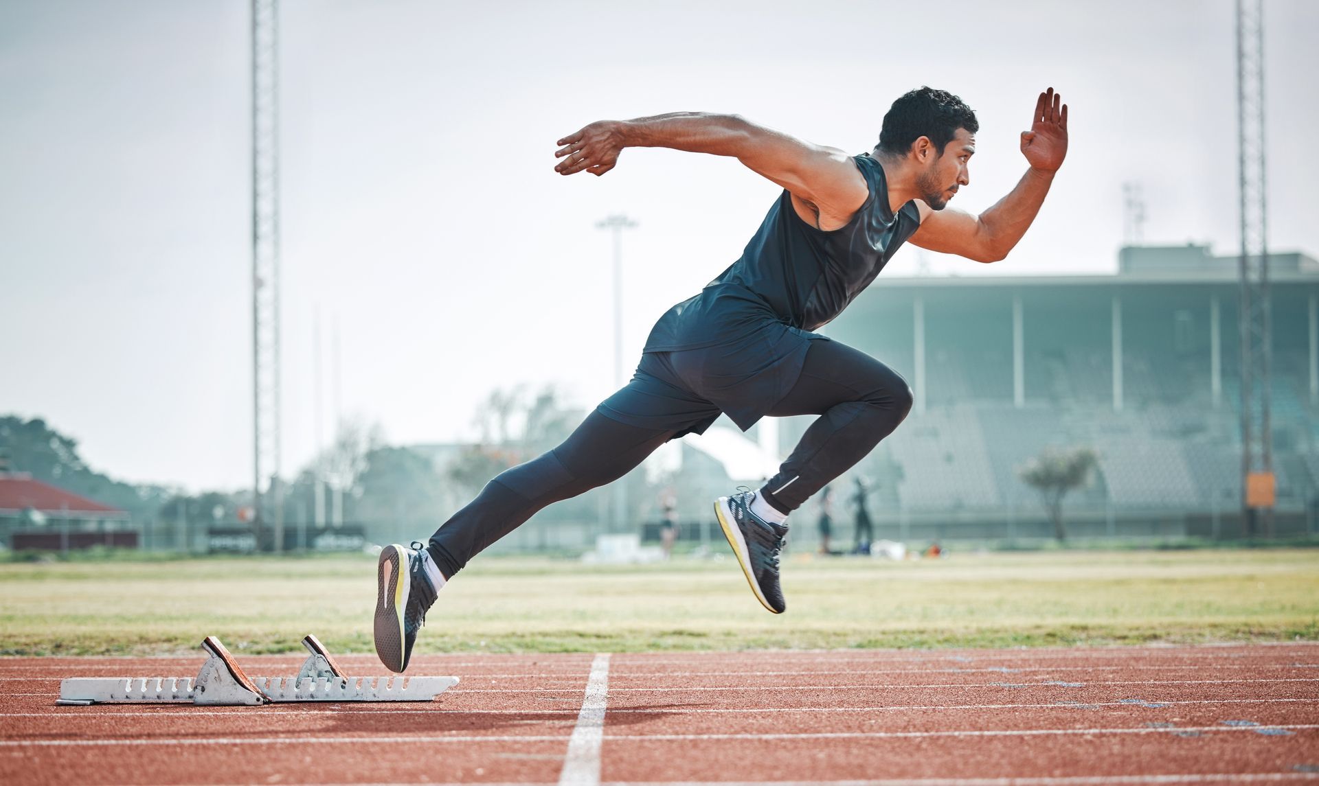 A man is running on a track in a stadium.