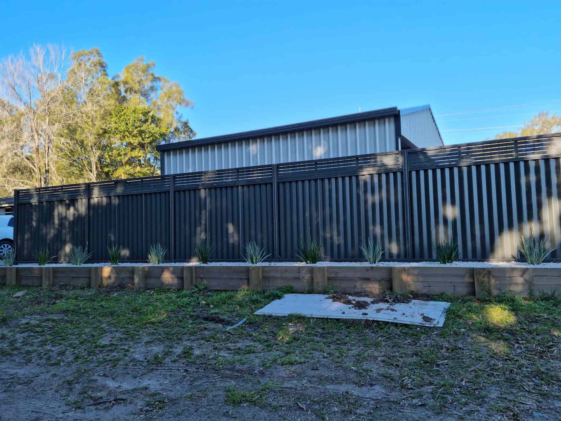A Black Fence Is Surrounding A Building In A Yard — Australian Advanced Fencing In Port Macquarie, NSW