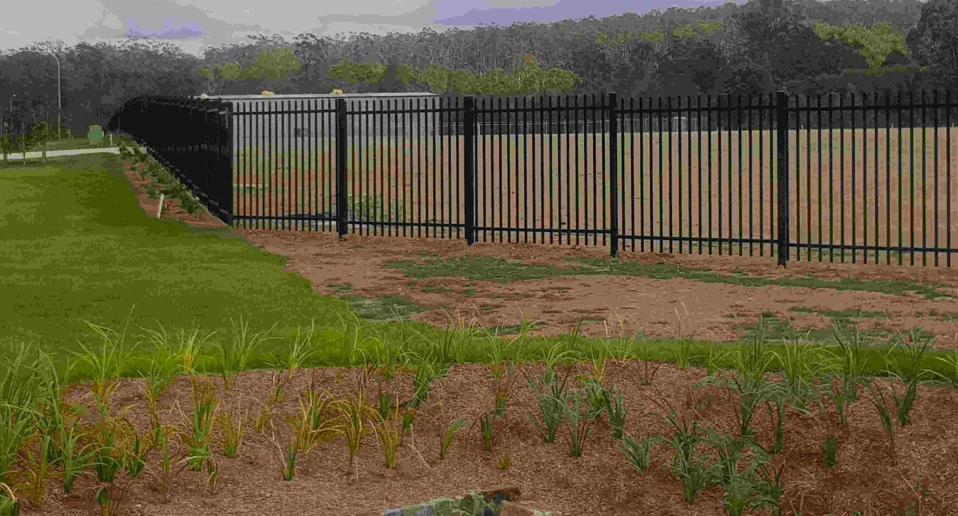 A Black Metal Fence Surrounds A Grassy Field — Australian Advanced Fencing In Port Macquarie, NSW