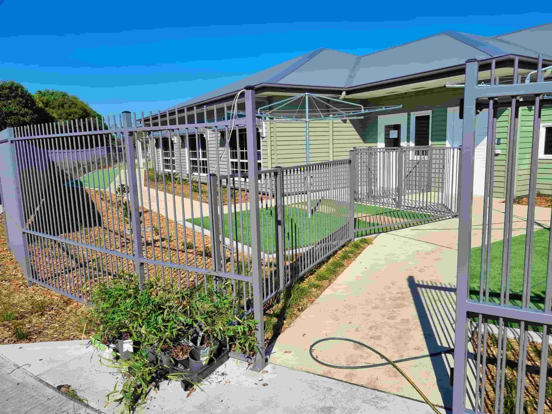 A Metal Fence Surrounds A Lush Green Field Of Grass — Australian Advanced Fencing In Laurieton, NSW