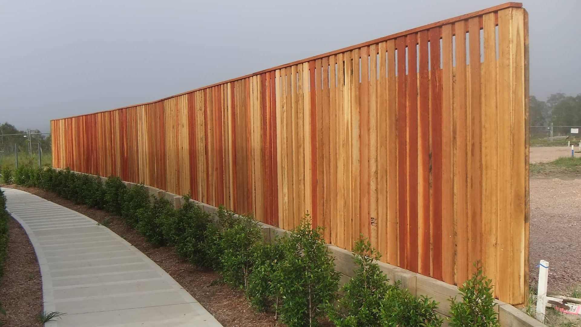 A Wooden Fence Is Casting Shadows On A Lush Green Lawn — Australian Advanced Fencing In Lake Cathie, NSW