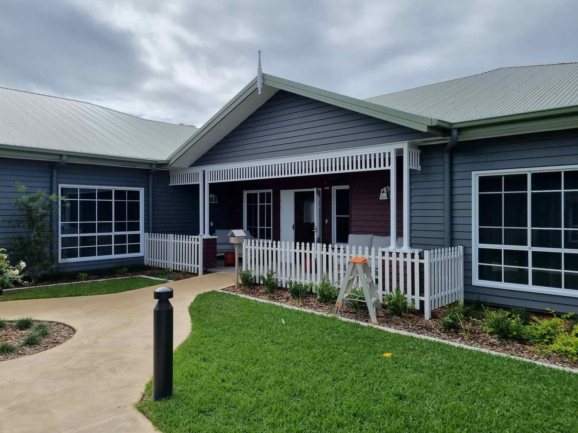 A Large House With A White Picket Fence In Front Of It — Australian Advanced Fencing In Port Macquarie, NSW