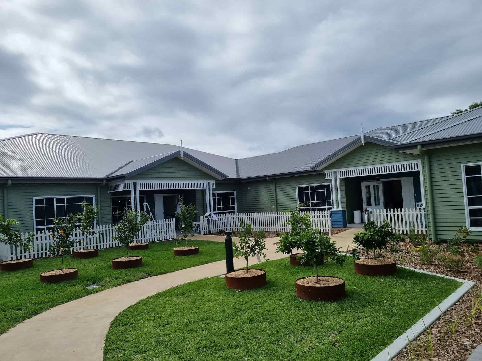 A Brown Sliding Gate Is Sitting Next To A White Fence — Australian Advanced Fencing In Lake Cathie, NSW
