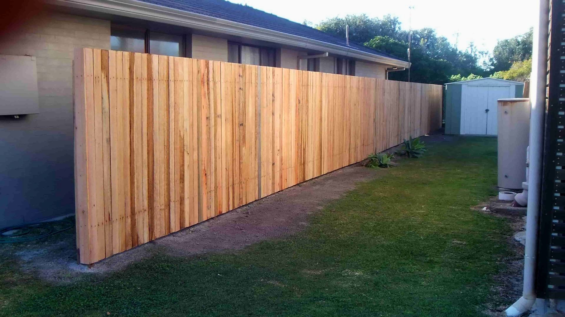 A Wooden Fence Is In The Backyard Of A House — Australian Advanced Fencing In Port Macquarie, NSW