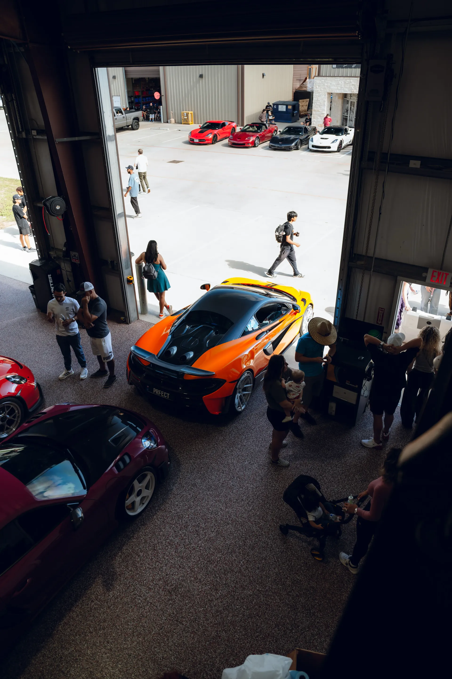 An orange and black McLaren sports car parked inside an open garage surrounded by a crowd of people. | Advance Automotive