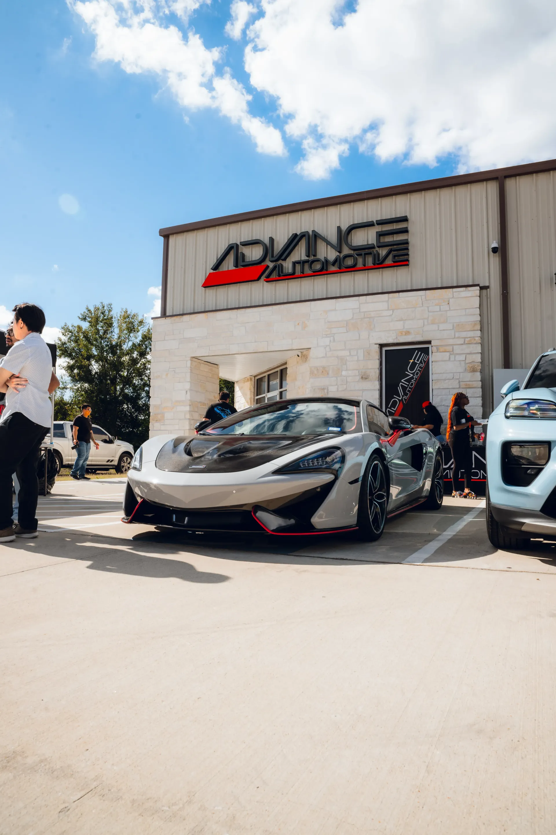 Silver McLaren sports car parked in front of Advance Automotive shop. | Advance Automotive