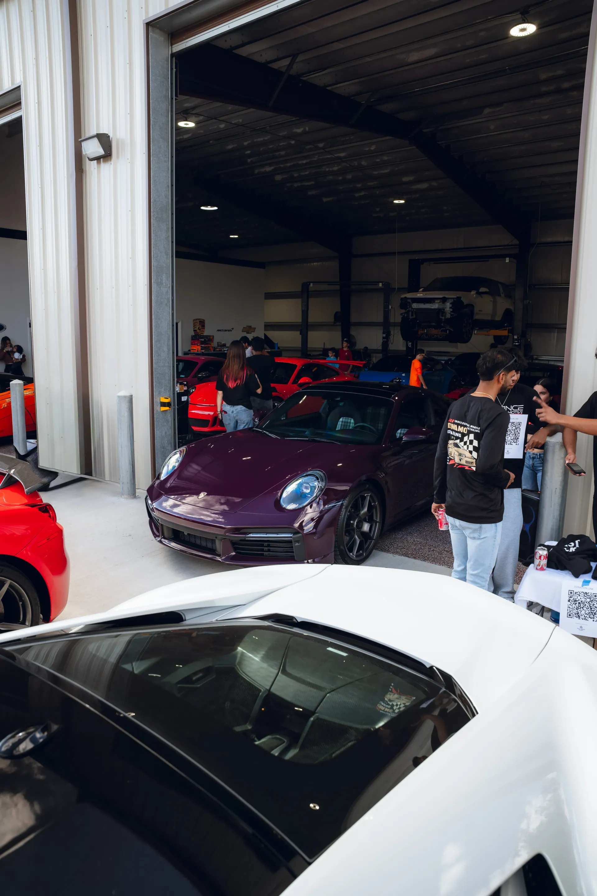 Purple sports car on display inside a garage with other cars and people. | Advance Automotive