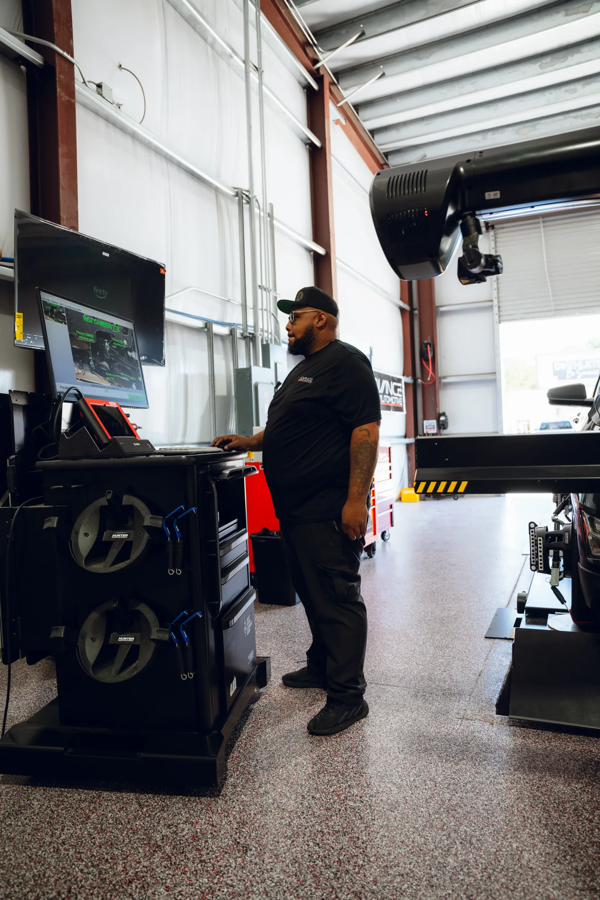 Mechanic in black uniform using a wheel alignment machine in a car repair shop. | Advance Automotive