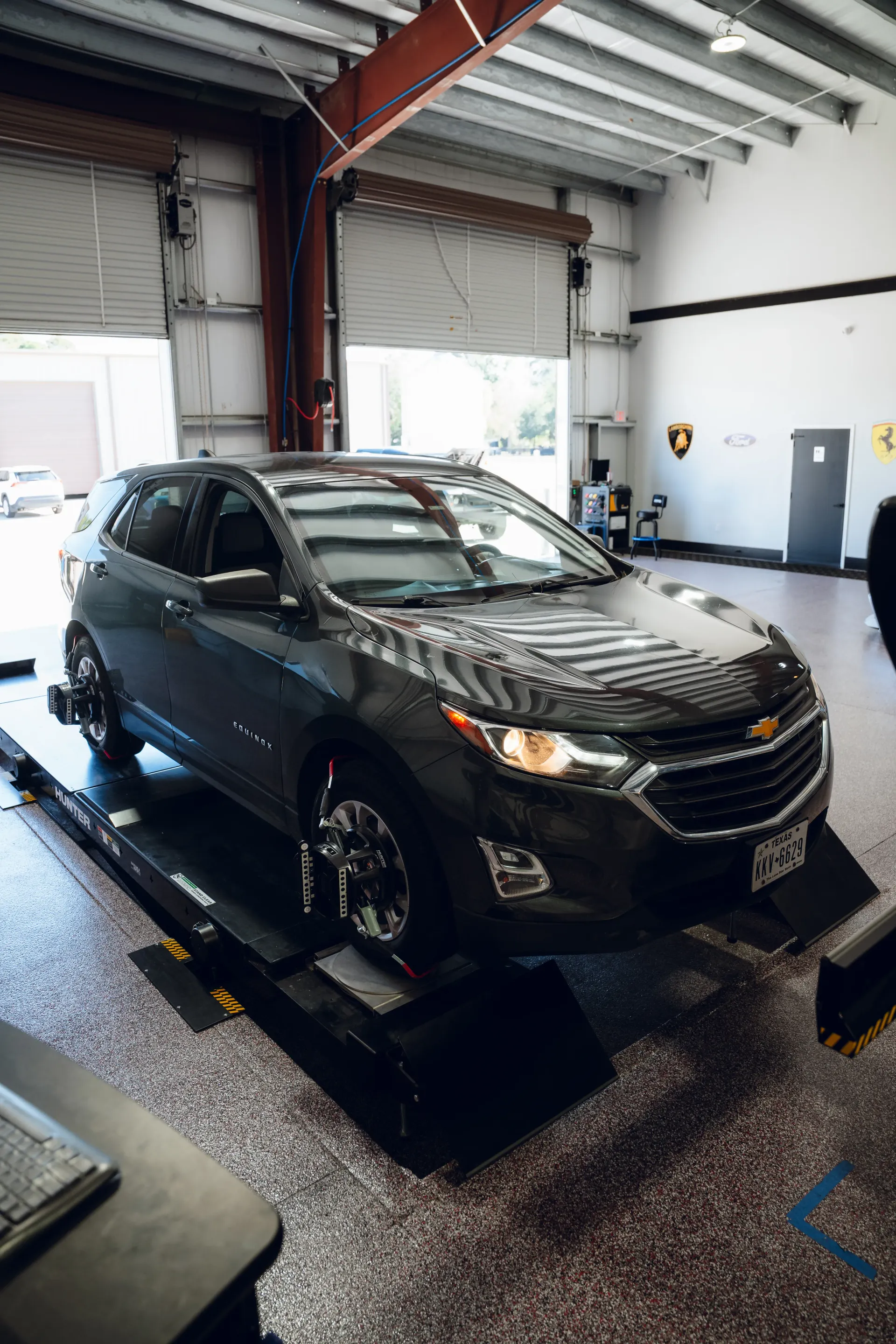 Gray SUV on alignment rack in a garage, open door in background. | Advance Automotive
