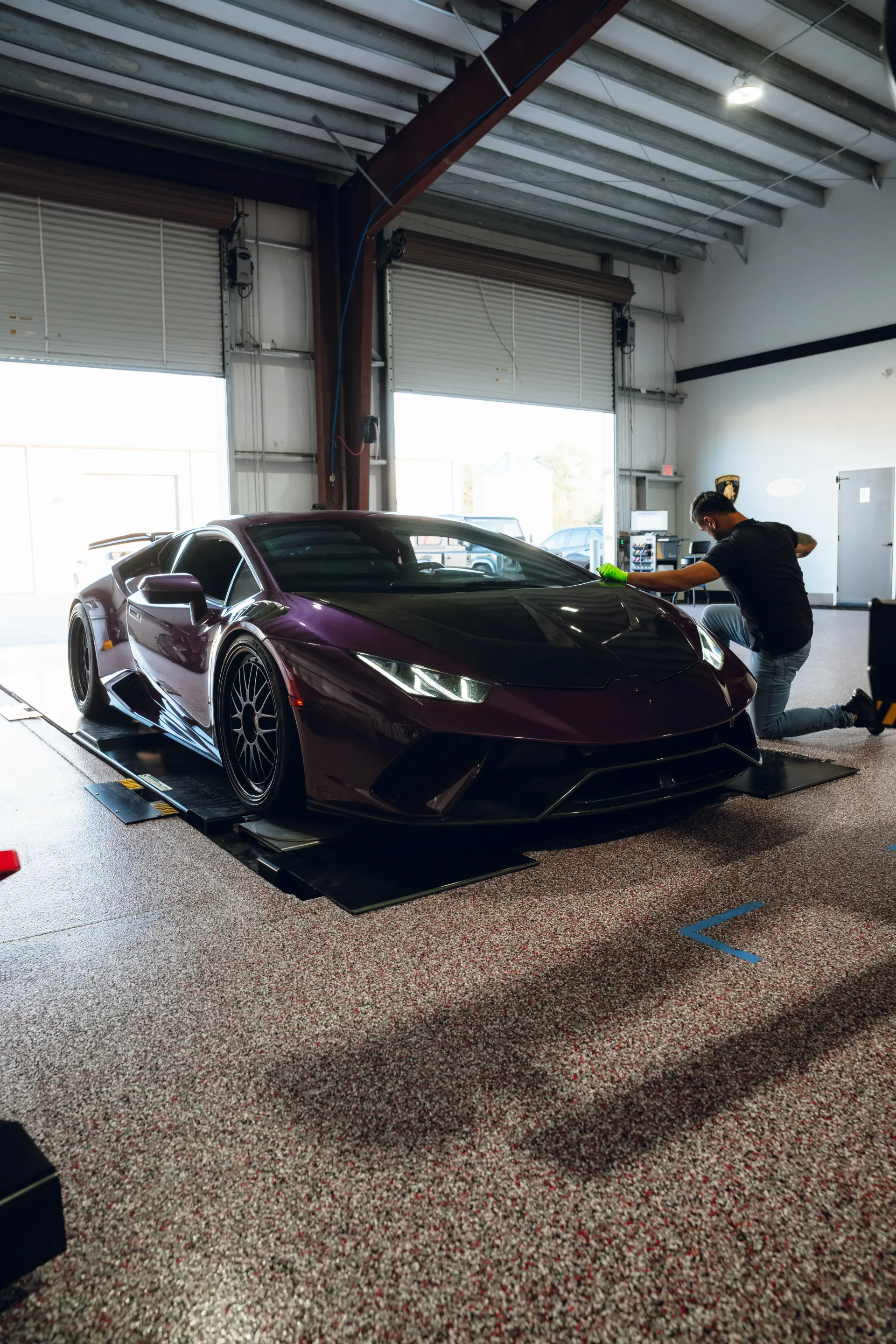 Purple Lamborghini inside a garage, being detailed by a person. | Advance Automotive