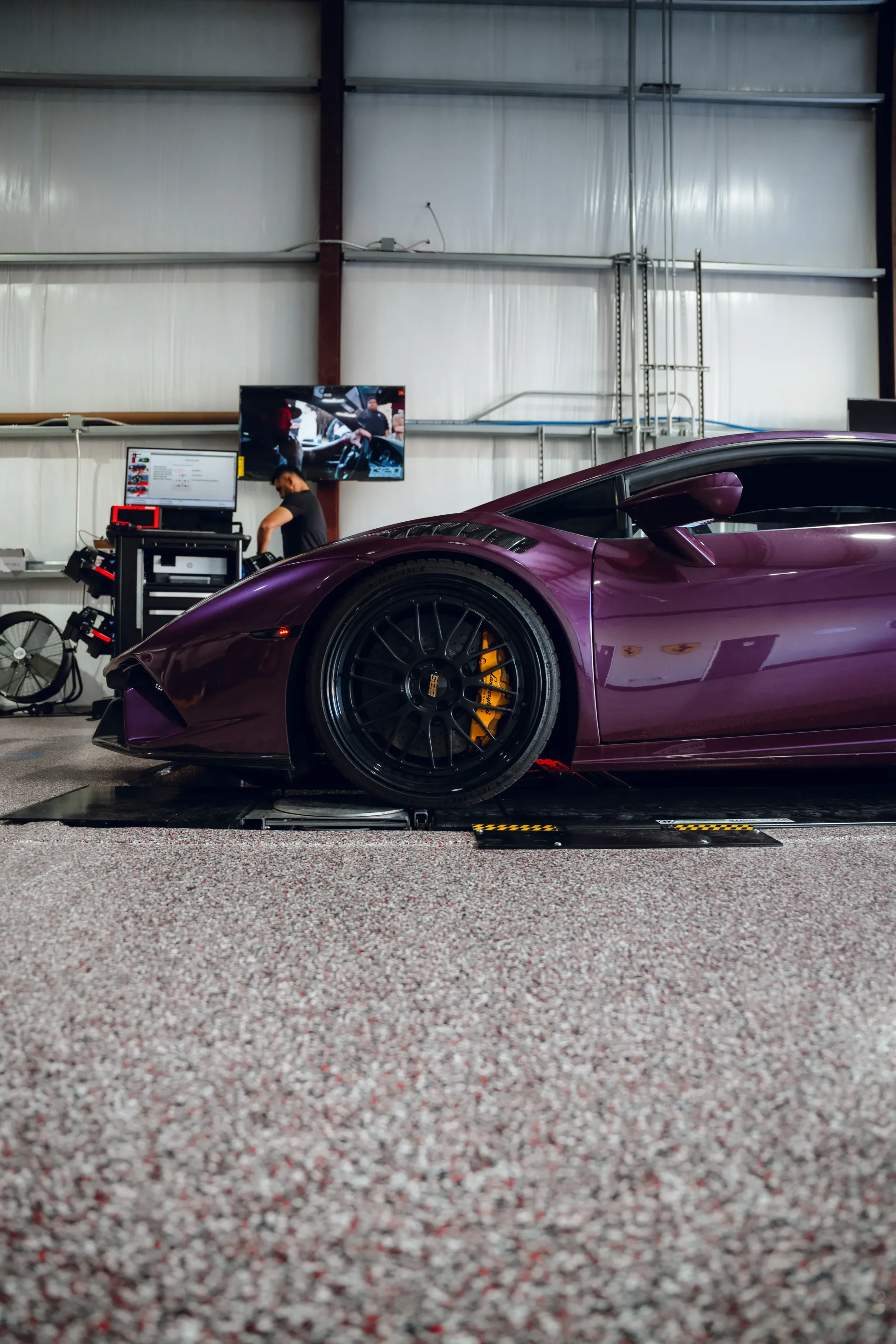 Purple Lamborghini sports car in a garage with black rims and orange brake calipers. | Advance Automotive