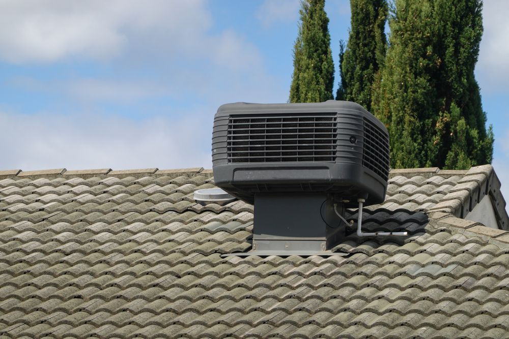 A Black Air Conditioner is Mounted on the Roof of a House — FVS Airconditioning & Electrical Pty Ltd in Karumba, QLD