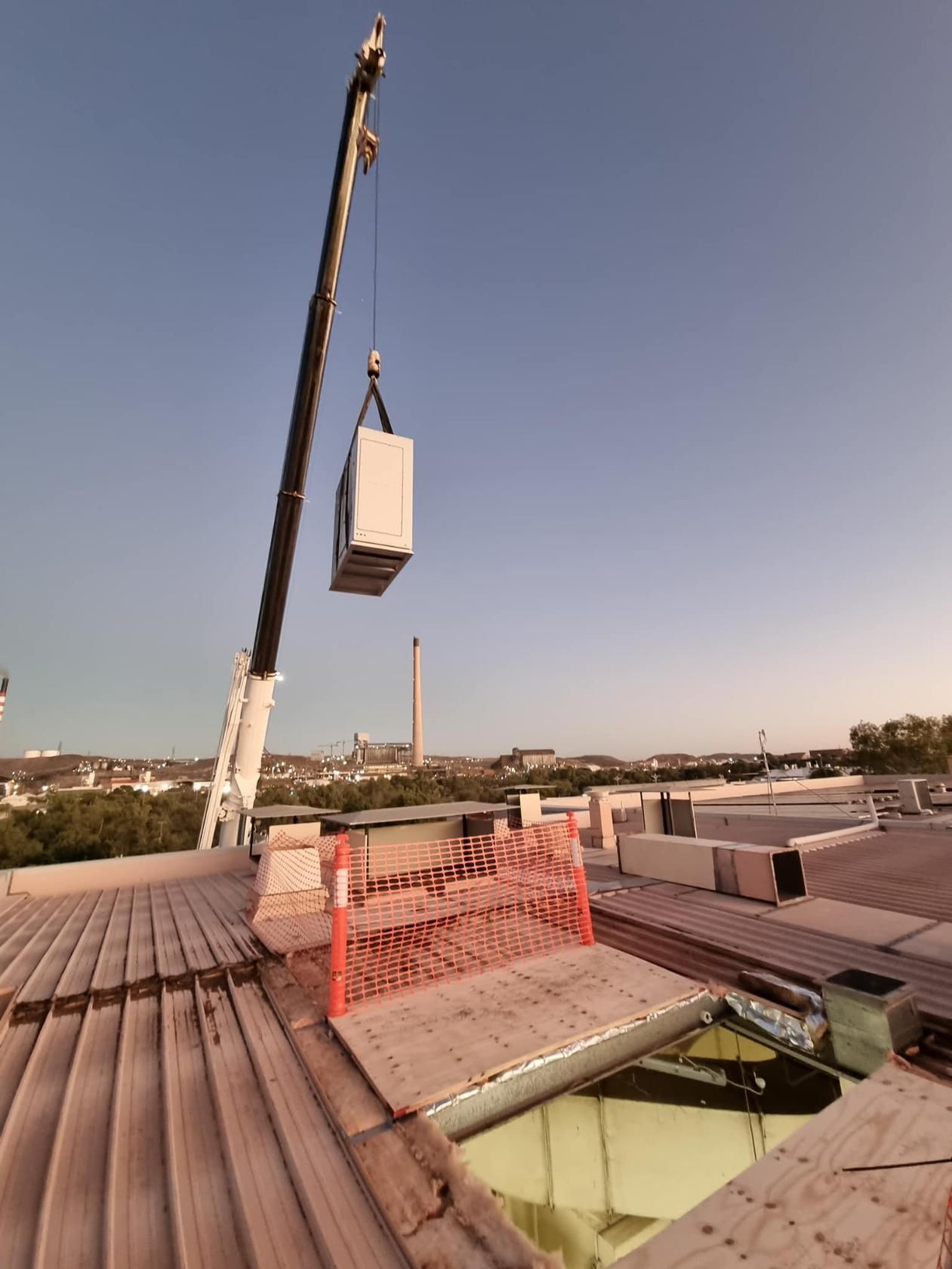 A Crane is Lifting a Box From the Roof of a Building — FVS Airconditioning & Electrical Pty Ltd in Doomadgee, QLD