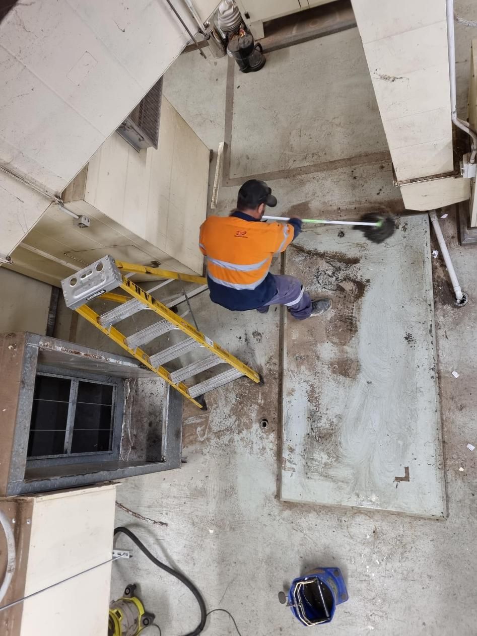 A Man is Sitting on a Ladder Cleaning the Floor of a Building — FVS Airconditioning & Electrical Pty Ltd in Ryan, QLD