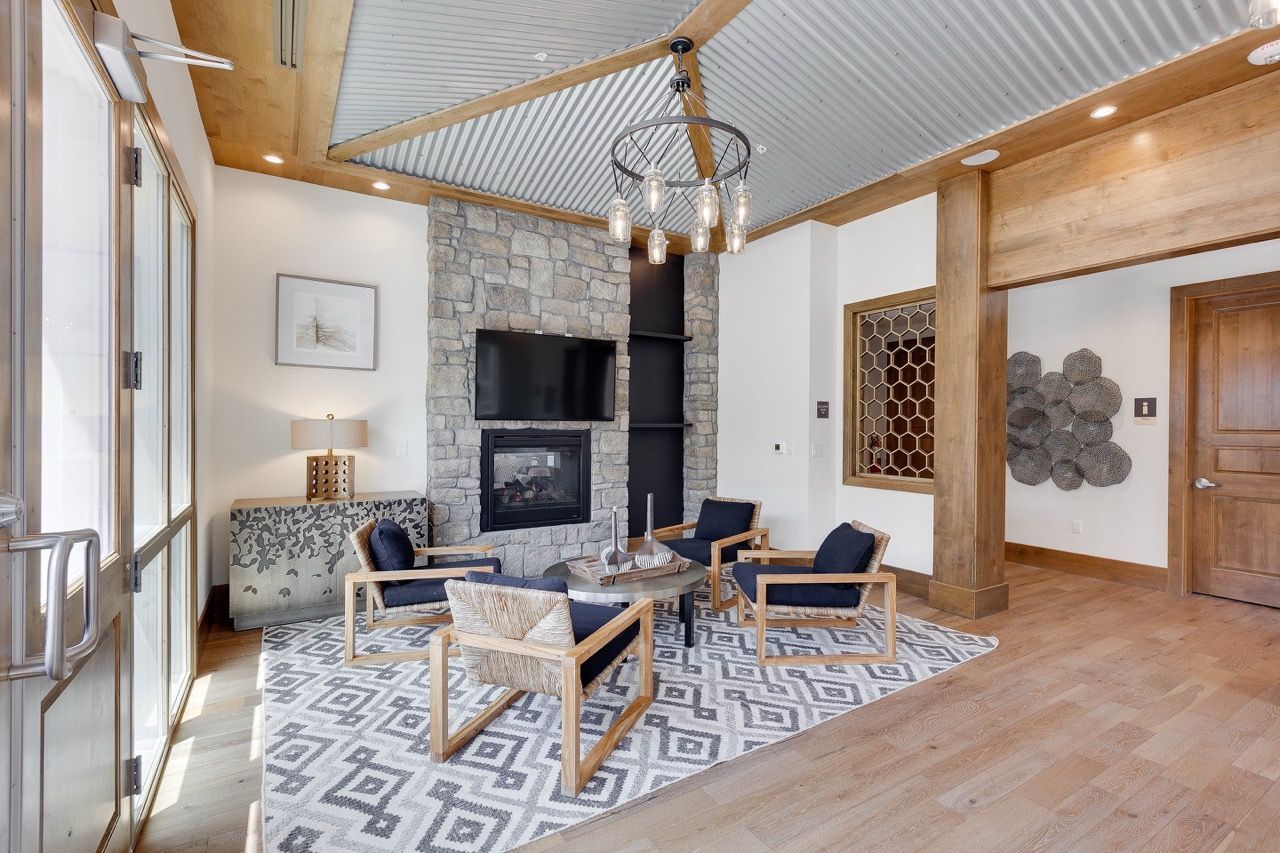 Living room in an apartment with a stone fireplace, TV, and contemporary seating.