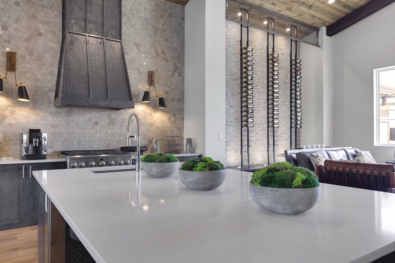 Modern apartment kitchen with a large white island, stainless steel appliances, and hex tile backsplash.