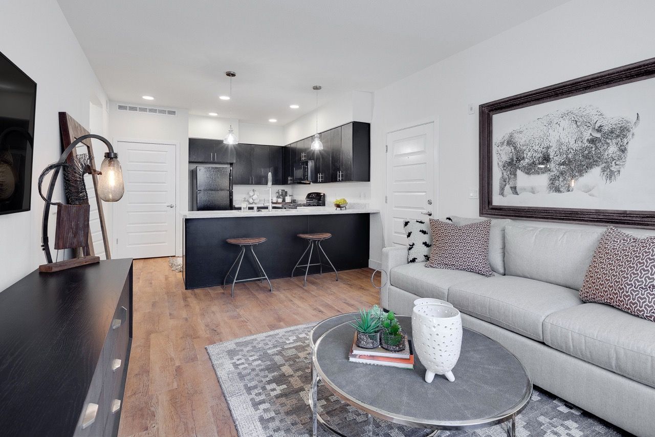Open-concept living area with gray sofa, round coffee table, and kitchen with a dark island.