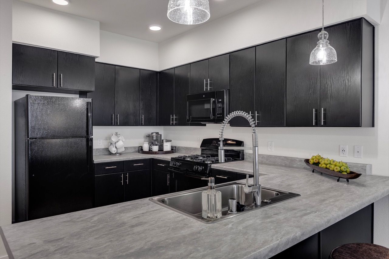 Modern black kitchen with stainless steel appliances and an island sink.