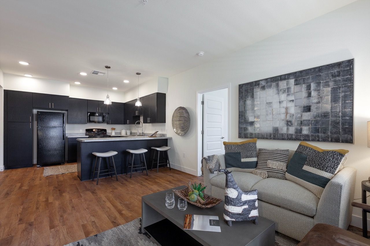 Open-concept living area with dark kitchen cabinets, an island, and a gray sofa.
