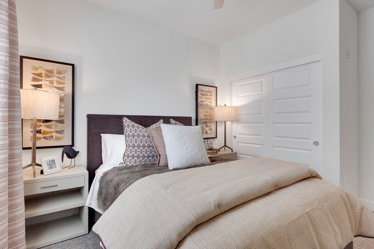 Bedroom with a bed, neutral bedding, two nightstands, lamps, and wall art.