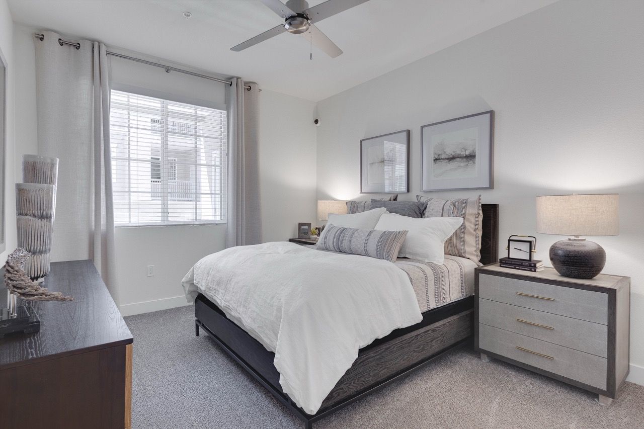 Bedroom in a modern apartment with a king bed, two nightstands, and a dresser.