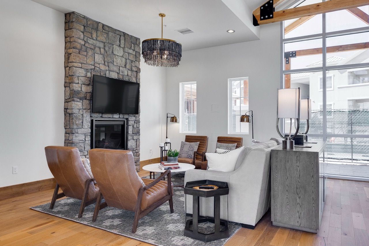 Living room with a stone fireplace, TV, leather chairs, and a white sofa.