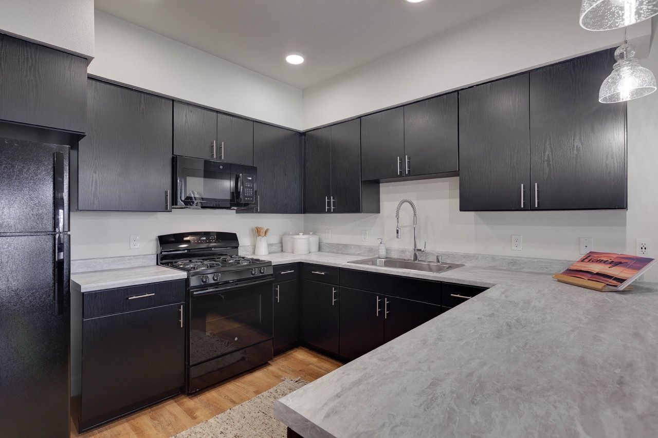 Modern kitchen with dark wood cabinets, stainless steel stove, microwave, and double sink.