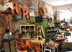 A colorful antique shop interior filled with retro decor, weird finds, rock shop items, costumes, vintage clothing, hats, and magazine racks.