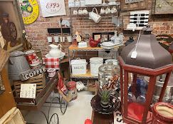 Antique shop display with vintage coffee signs, jars, and metal containers on shelves and tables