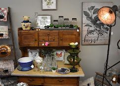 A vintage shop assistant sourcing antique decor from shelves and displays in a warmly lit store.