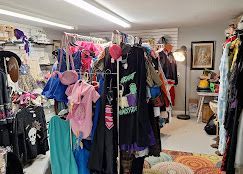 Vintage clothing, hats, and costumes arranged on racks in a whimsical antique store.
