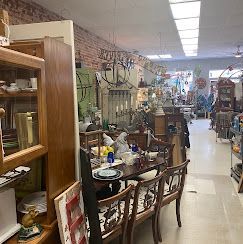 Antique shop aisle with furniture, glassware, and decor displayed on shelves and tables