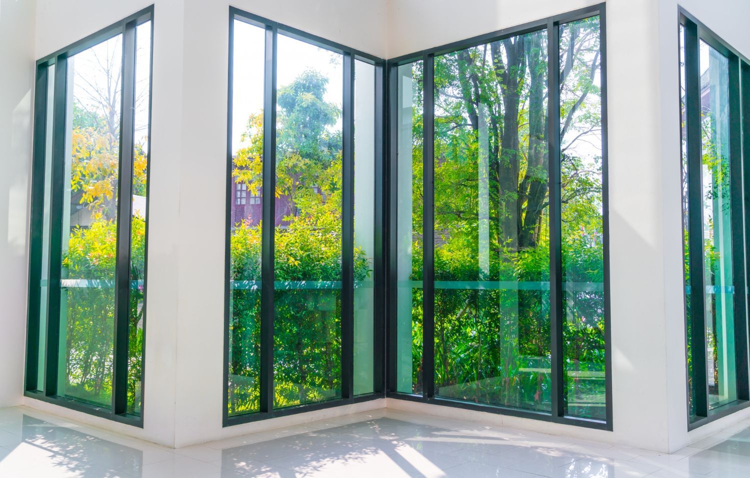 A room with a lot of windows and trees reflected in the windows.