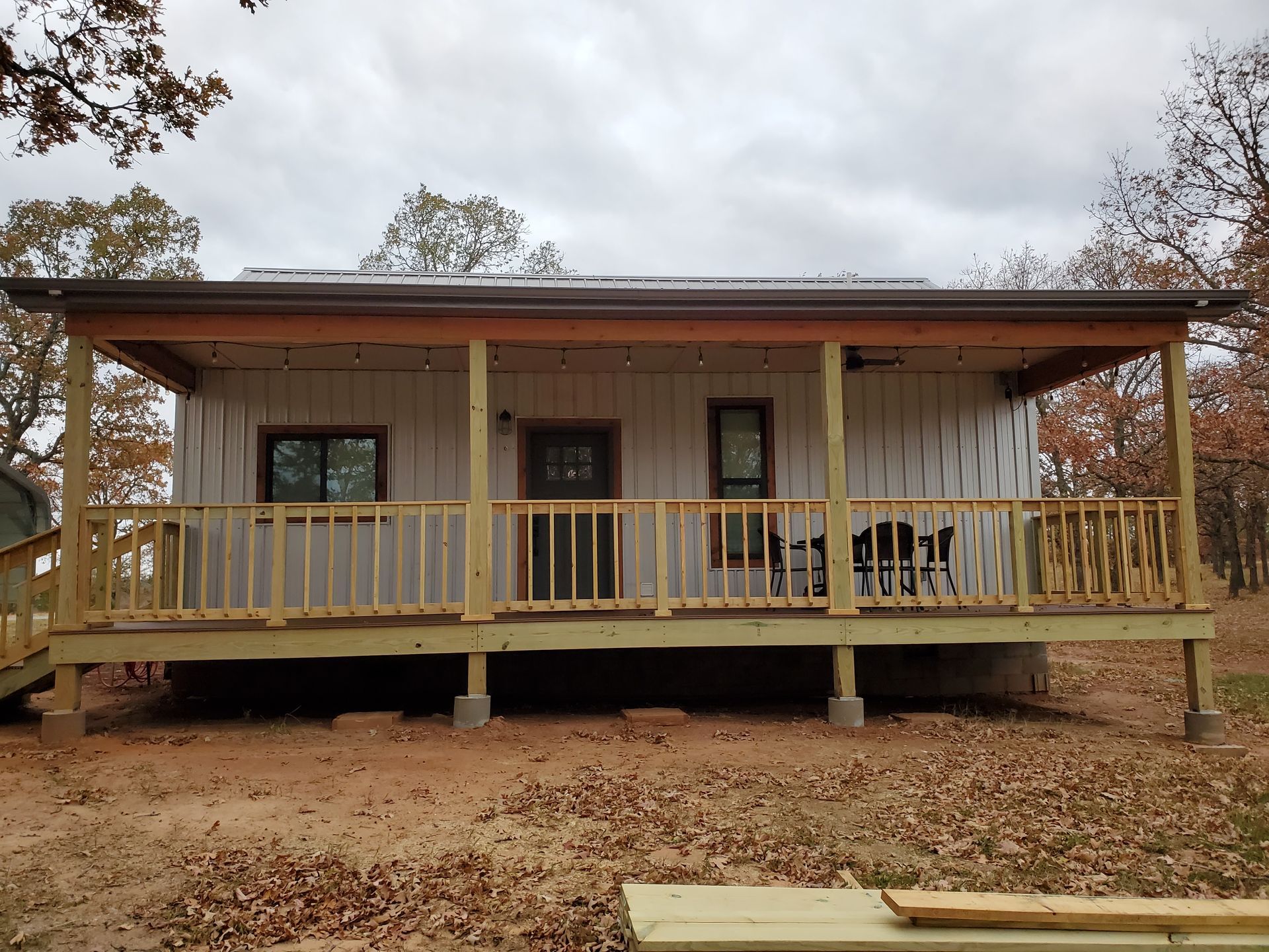 A small white house with a porch and a wooden deck.