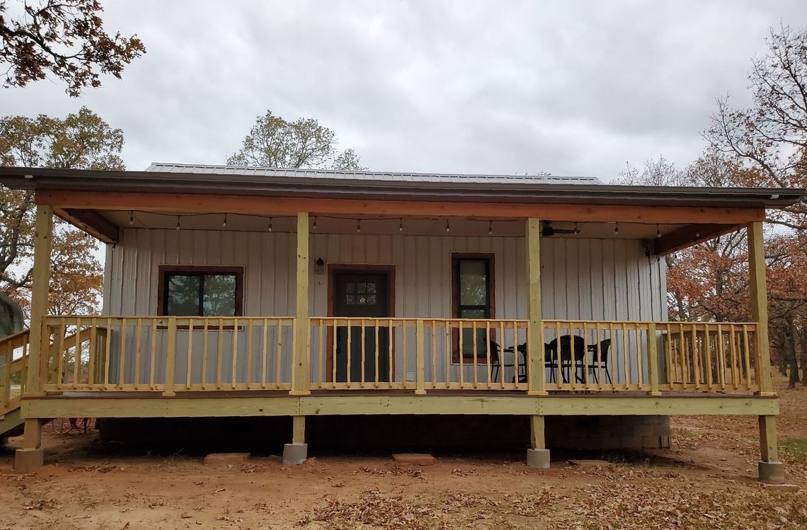 A small white house with a porch and a wooden deck.