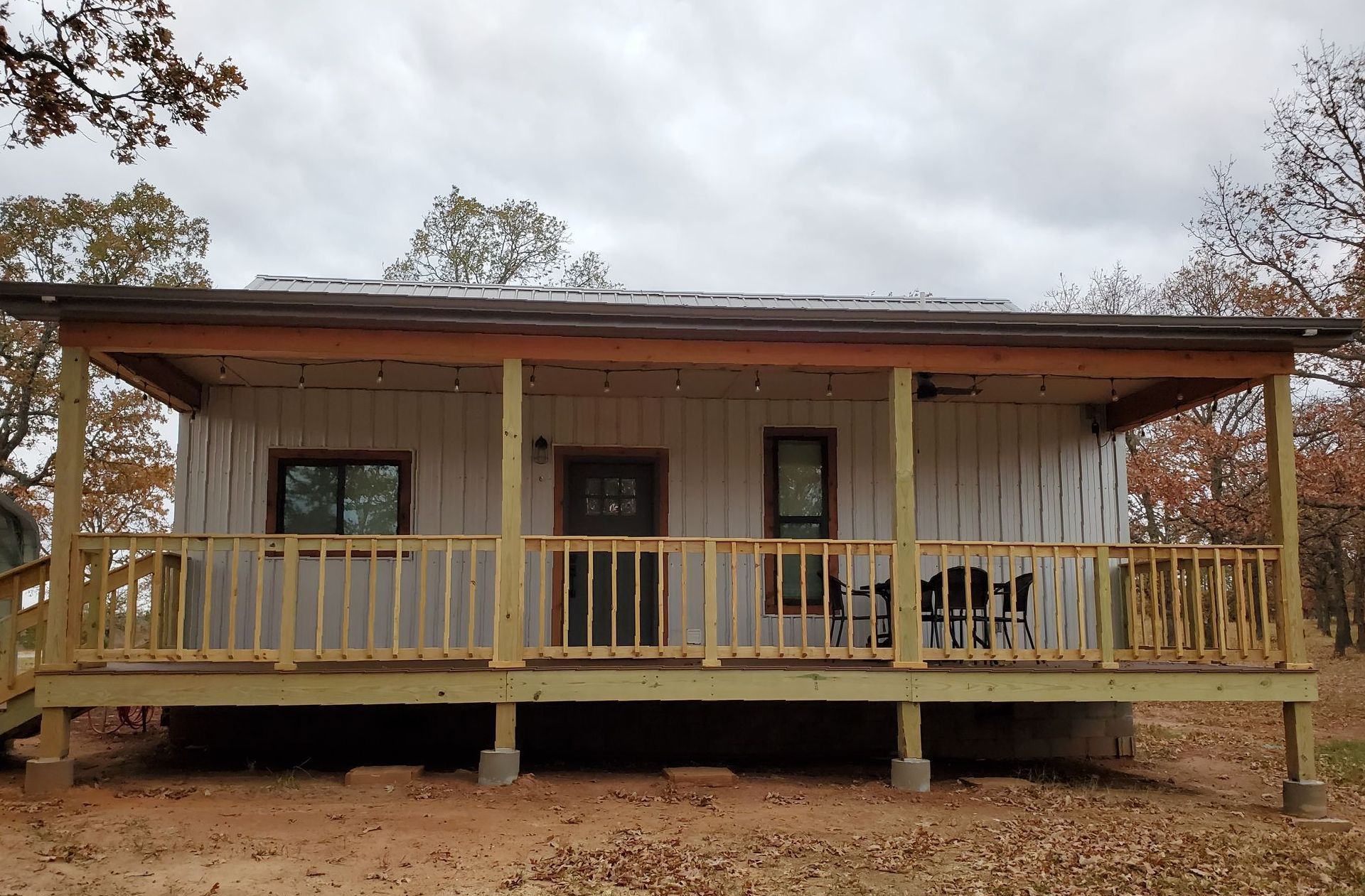 A small white house with a porch and a wooden deck.