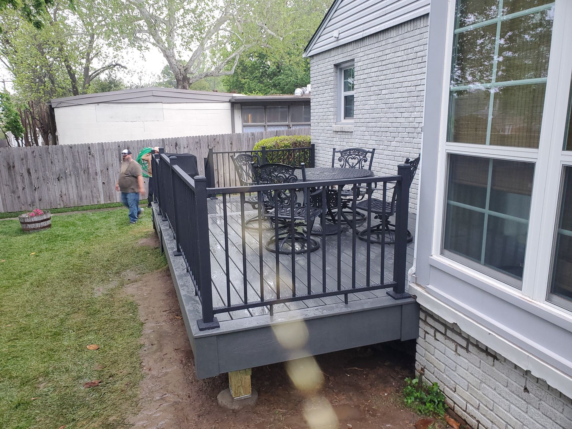 A deck with a table and chairs is in the backyard of a house.
