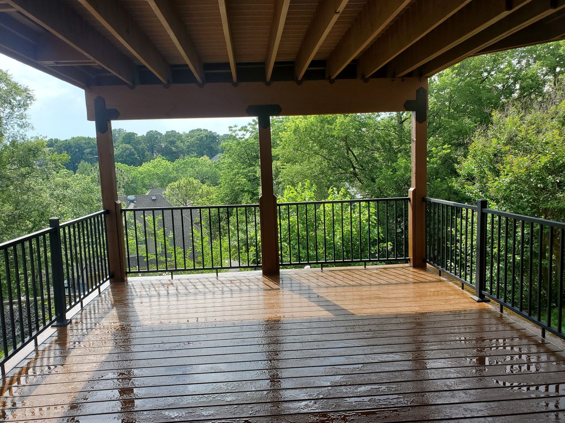 An empty deck with a railing and trees in the background.