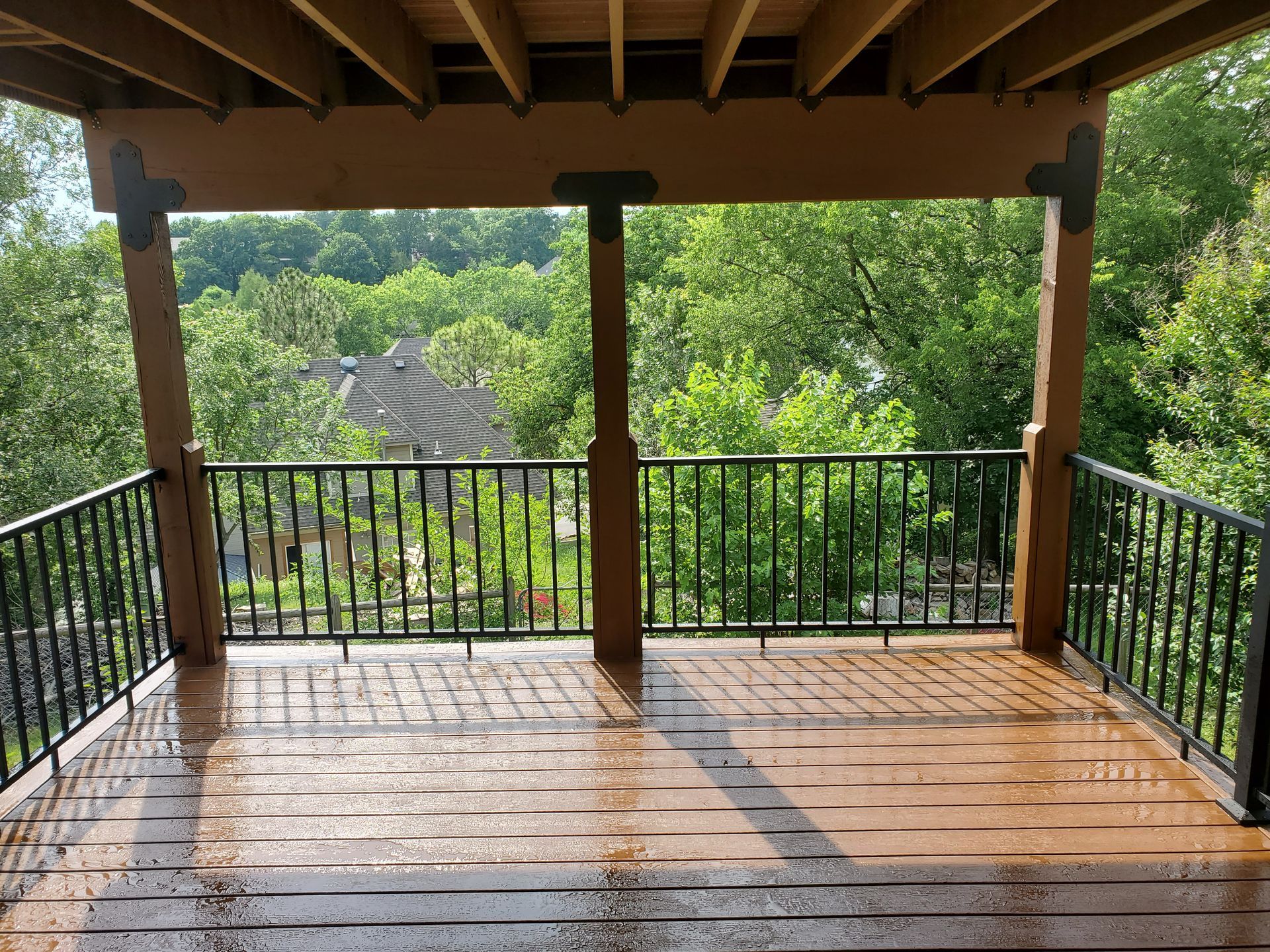 A wooden deck with a metal railing and trees in the background.