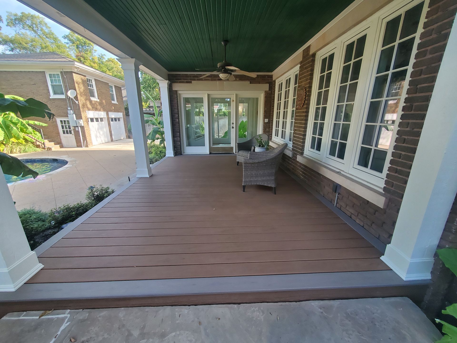 A large porch with a chair and a ceiling fan