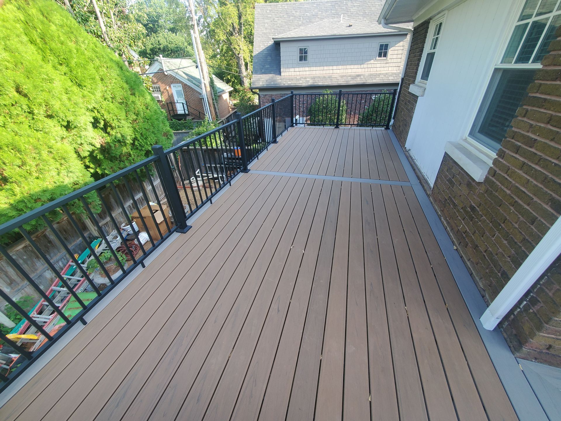 A wooden deck with a metal railing is sitting on top of a brick house.