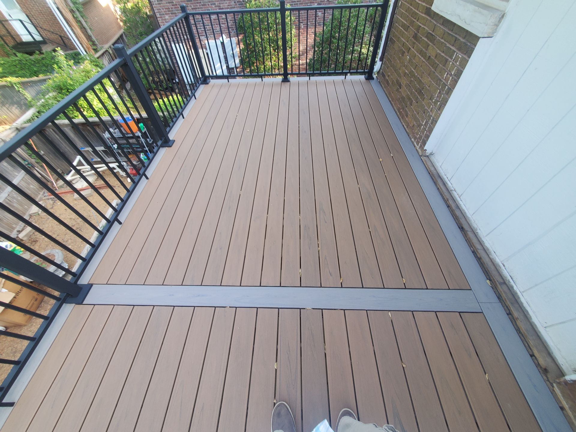A person is standing on a wooden deck with a metal railing.