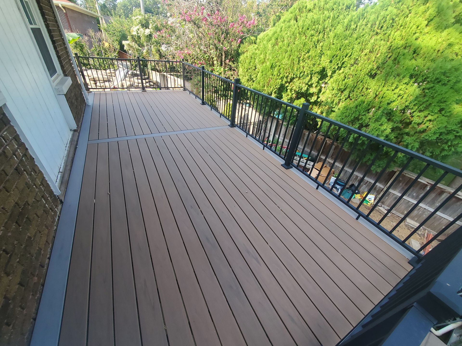 A wooden deck with a metal railing and trees in the background.